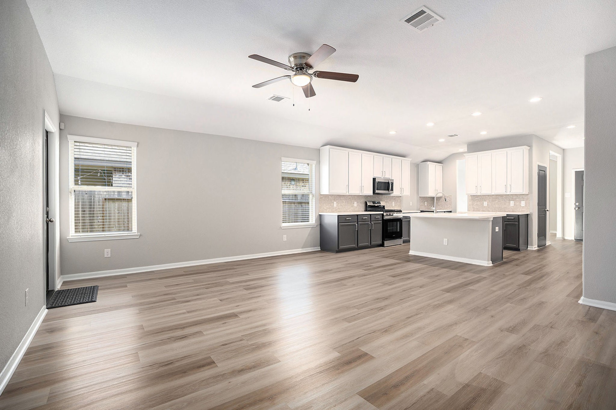 4027 Spurwing Lane Baytown, TX 77521 - Photo 7 of 34 This photo showcases a spacious, open-concept living area. The modern kitchen features white cabinetry, stainless steel appliances, and a large island ready for barstools.