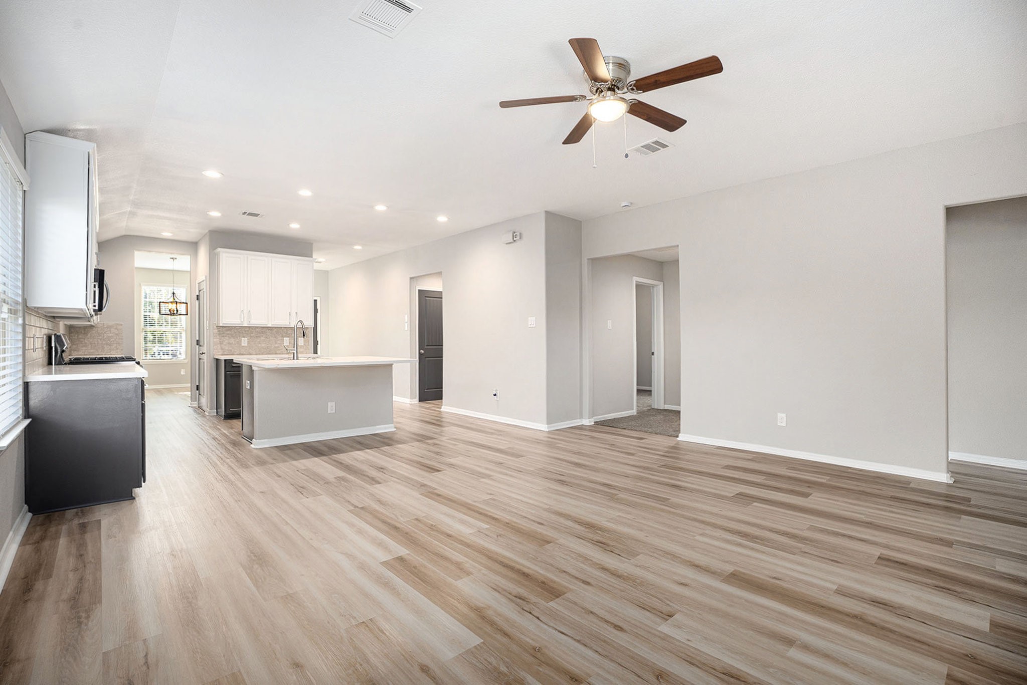 4027 Spurwing Lane Baytown, TX 77521 - Photo 8 of 34 This spacious, open-concept living area features new flooring and recessed lighting. The kitchen boasts a large island, stainless steel appliances, and sleek cabinetry, offering a bright and welcoming space for entertaining.