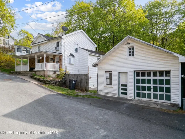 a view of a white house next to a yard and garage