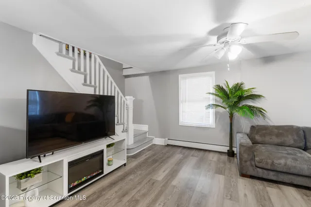 a view of a dining room and livingroom with furniture wooden floor a rug a painting and a chandelier