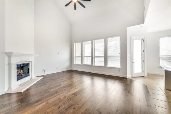 an empty room with wooden floor fireplace and windows