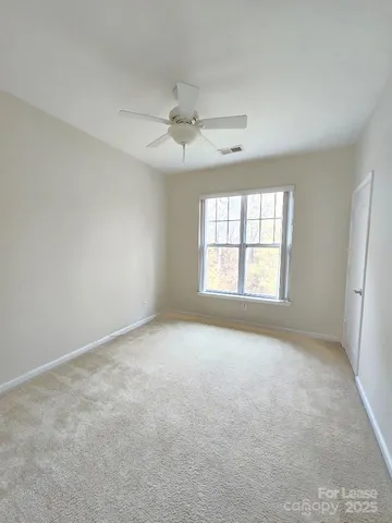 an empty room with a window and a ceiling fan