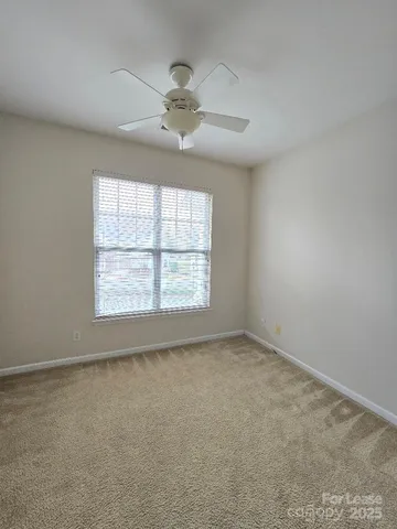an empty room with a chandelier fan and windows