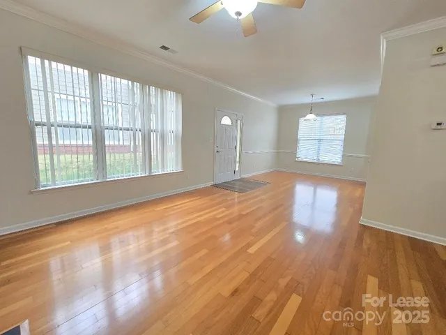 a view of an empty room with a window and wooden floor