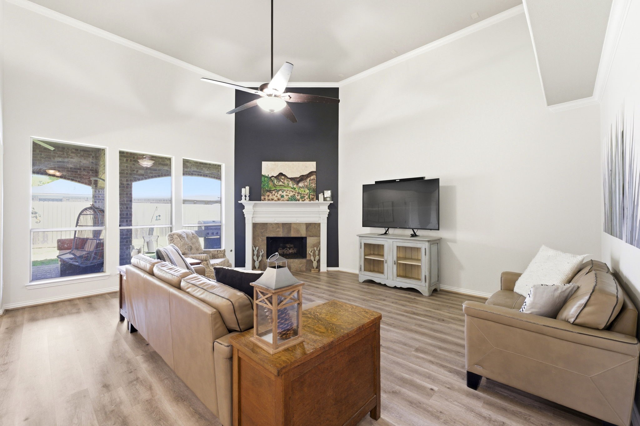 27502 Chris Ridge Court Spring, TX 77386 - Photo 8 of 37 Spacious living room with high ceilings, featuring a modern ceiling fan, cozy fireplace, and large windows offering plenty of natural light.