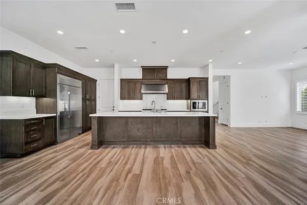 a large kitchen with kitchen island a sink dishwasher a stove and a refrigerator with wooden floor