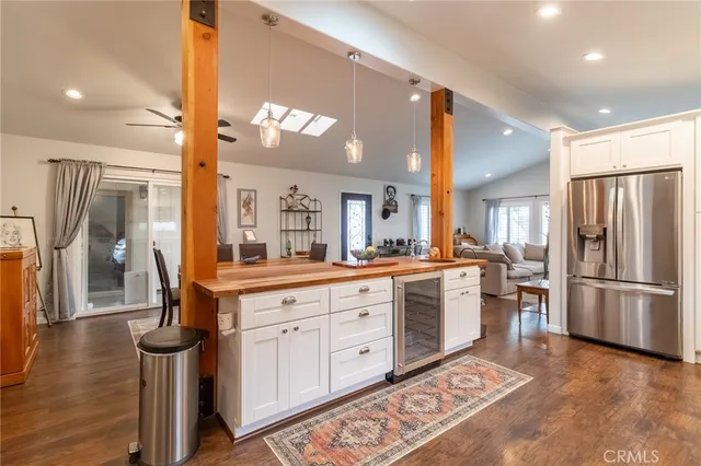 a large kitchen with stainless steel appliances kitchen island granite countertop a refrigerator a stove a sink and a dining table with wooden floor