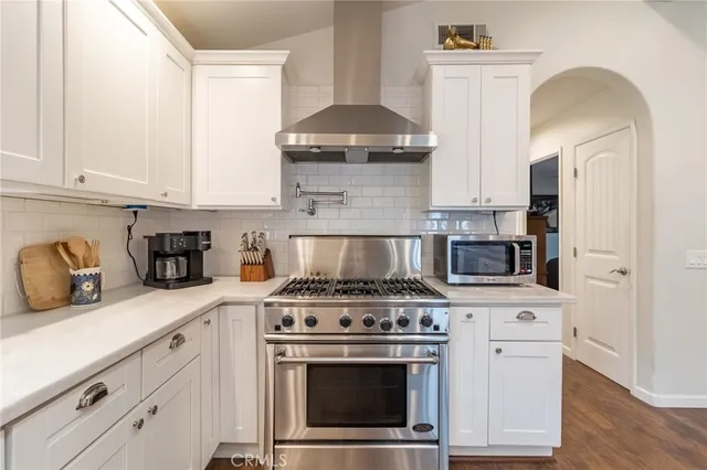 a kitchen with stainless steel appliances granite countertop a stove and a white cabinets
