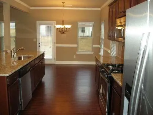 a kitchen with granite countertop a refrigerator a sink and wooden floor