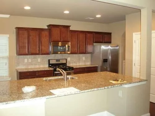 a kitchen with stainless steel appliances granite countertop a refrigerator a stove and a sink with wooden cabinets