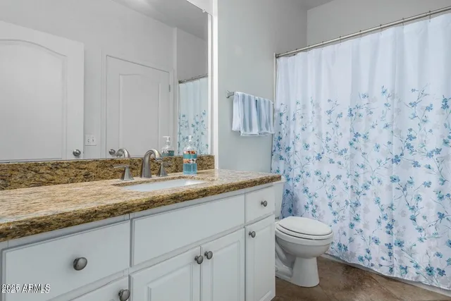 a bathroom with a granite countertop sink and a toilet