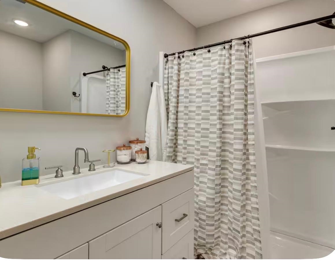 110 Bogey Loop Counce, TN 38326 - Photo 14 of 18 Bathroom featuring a rectangular gold-framed mirror, an integrated sink with a brushed nickel faucet, a white vanity with paneled doors and drawer, and a shower-tub combination with built-in shelving
