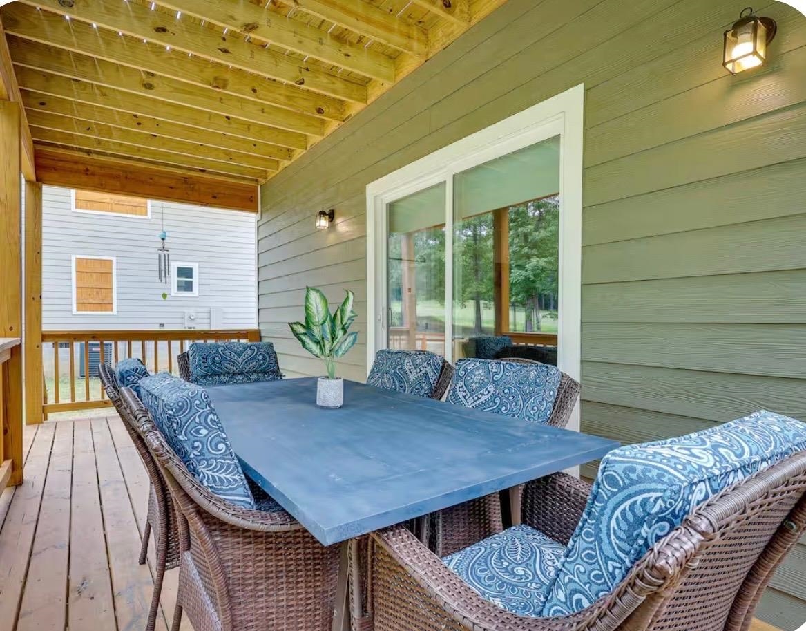 110 Bogey Loop Counce, TN 38326 - Photo 16 of 18 Covered wood-finish deck with exposed beam ceiling, featuring a sliding glass door and wall-mounted outdoor lighting
