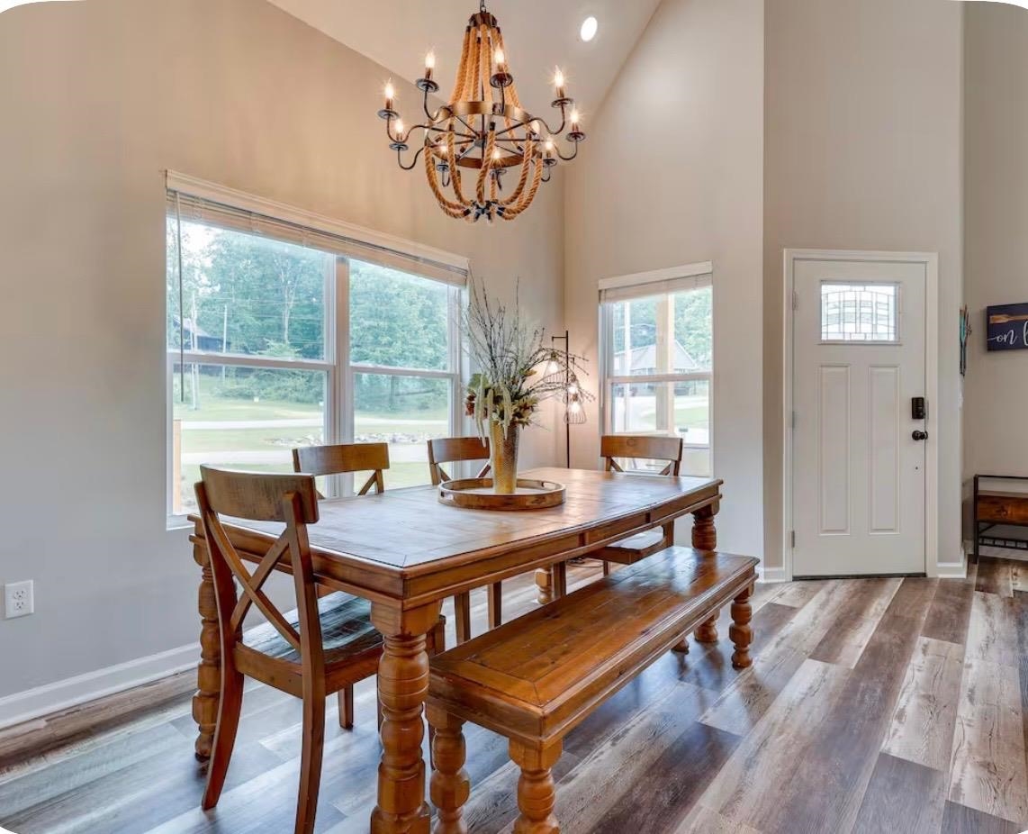 110 Bogey Loop Counce, TN 38326 - Photo 4 of 18 Vaulted ceiling dining area featuring a decorative chandelier, multiple windows, and wood-finish flooring
