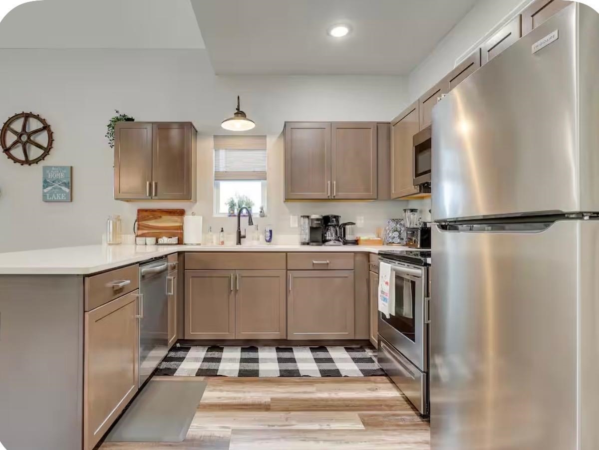 110 Bogey Loop Counce, TN 38326 - Photo 6 of 18 Contemporary kitchen featuring a full suite of stainless steel appliances, light wood-finish flooring, white countertops, and neutral cabinetry