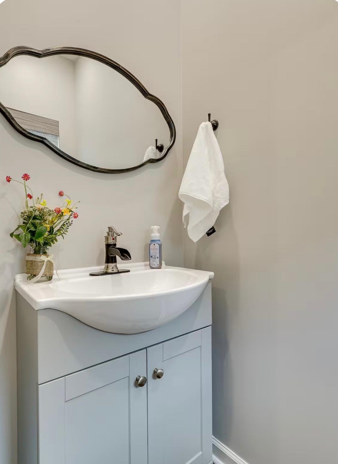 110 Bogey Loop Counce, TN 38326 - Photo 7 of 18 Powder room featuring a light gray vanity with brushed nickel hardware, a curved white porcelain sink, and a black and chrome faucet
