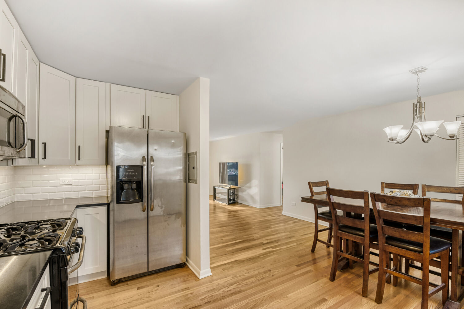 1710 Dempster Street, Unit B Park Ridge, IL 60068 - Photo 18 of 27 a kitchen with stainless steel appliances a refrigerator a stove a dining table and chairs with wooden floor