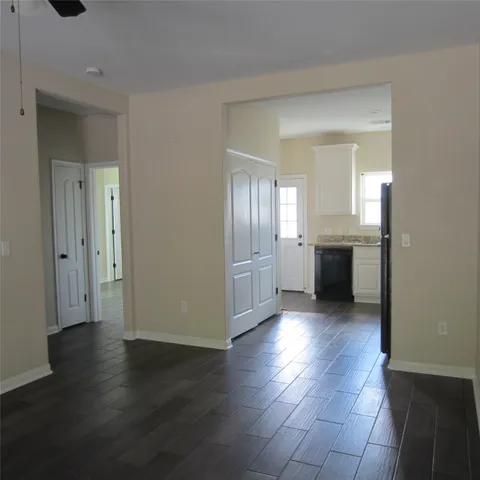 an empty room with wooden floor kitchen view and bathroom view