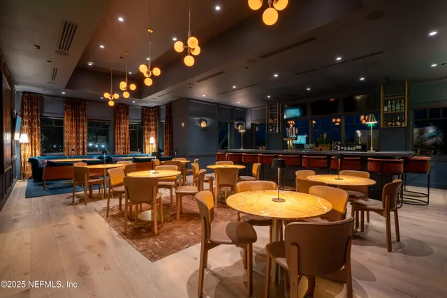 a dining room with furniture a floor to ceiling window and wooden floor