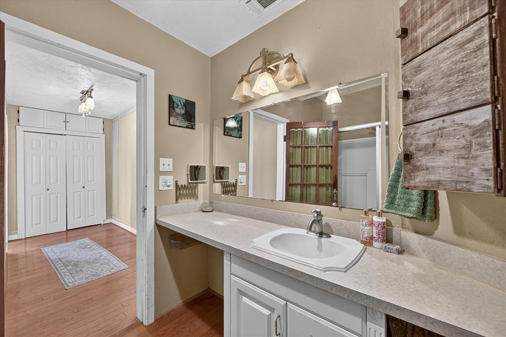 304 East Main Street Itasca, TX 76055 - Photo 28 of 38 Vanity with integrated sink, expansive countertop, and wall-mounted mirror