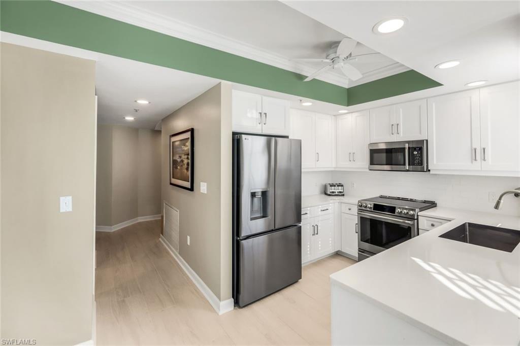 300 Dunes Boulevard, Unit 201 Naples, FL 34110 - Photo 15 of 50 a kitchen with stainless steel appliances granite countertop white refrigerator a stove top oven a sink and dishwasher
