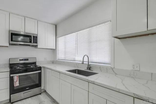 a kitchen with stainless steel appliances a stove a sink a microwave and cabinets