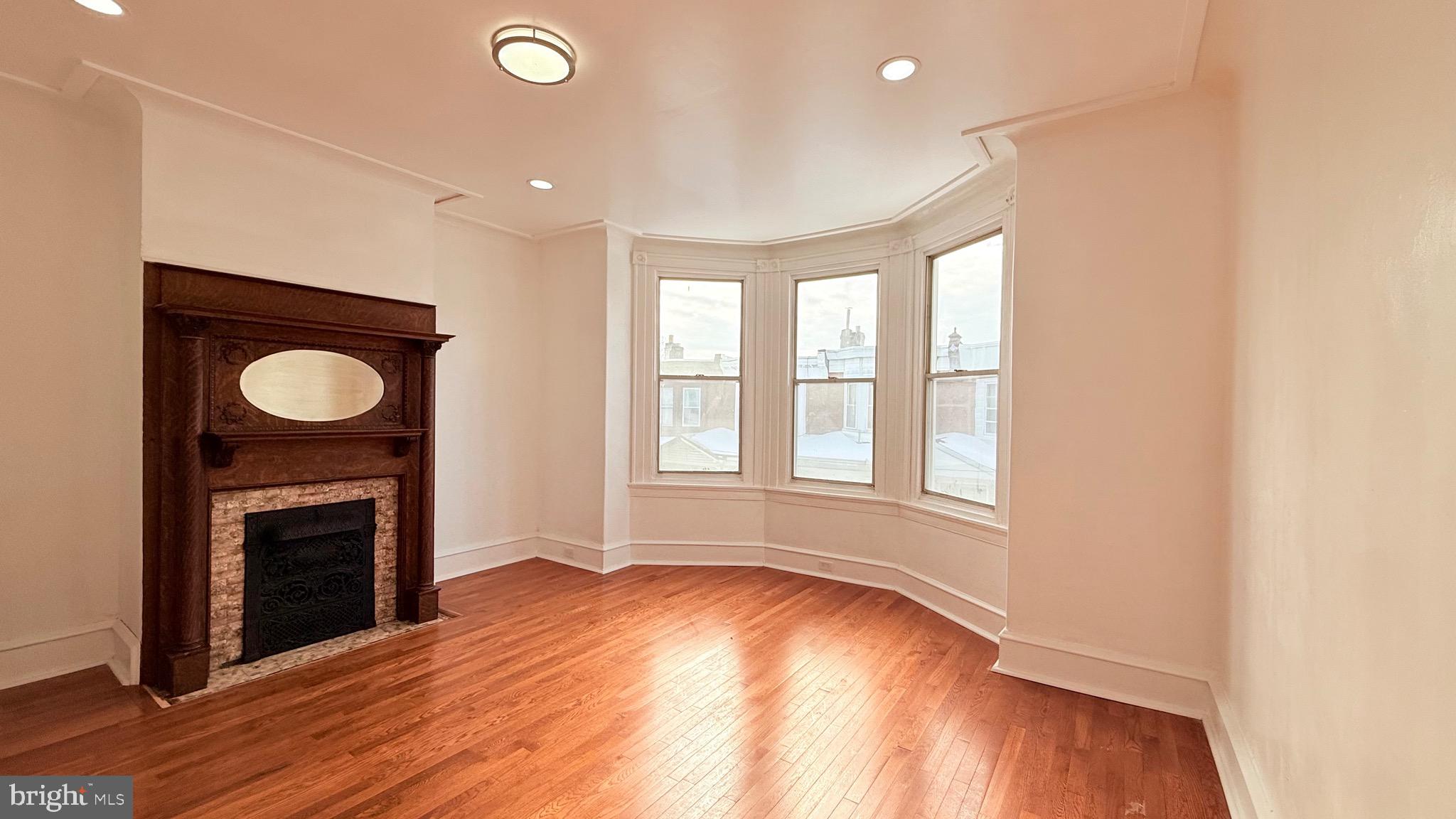 1333 Colwyn Street Philadelphia, PA 19140 - Photo 15 of 38 an empty room with wooden floor a fireplace and a window