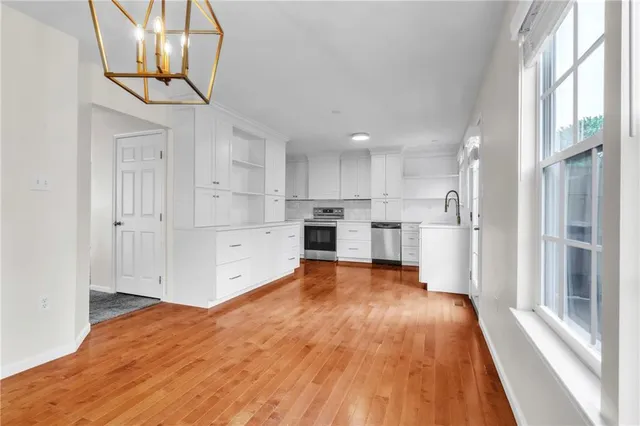 a open kitchen with white cabinets and wooden floor