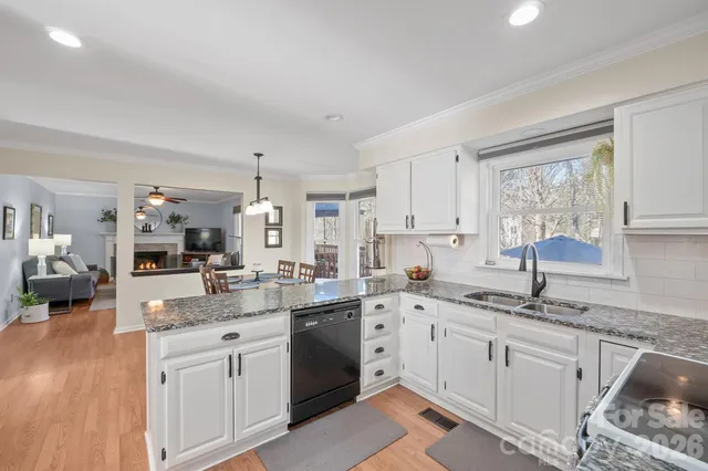 a kitchen with a sink dishwasher a stove and white cabinets with wooden floor