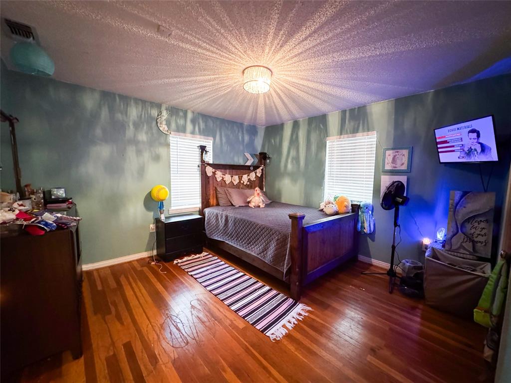 1303 Grand Central Avenue O'Brien, TX 79539 - Photo 21 of 40 a bedroom with a bed and wooden floor