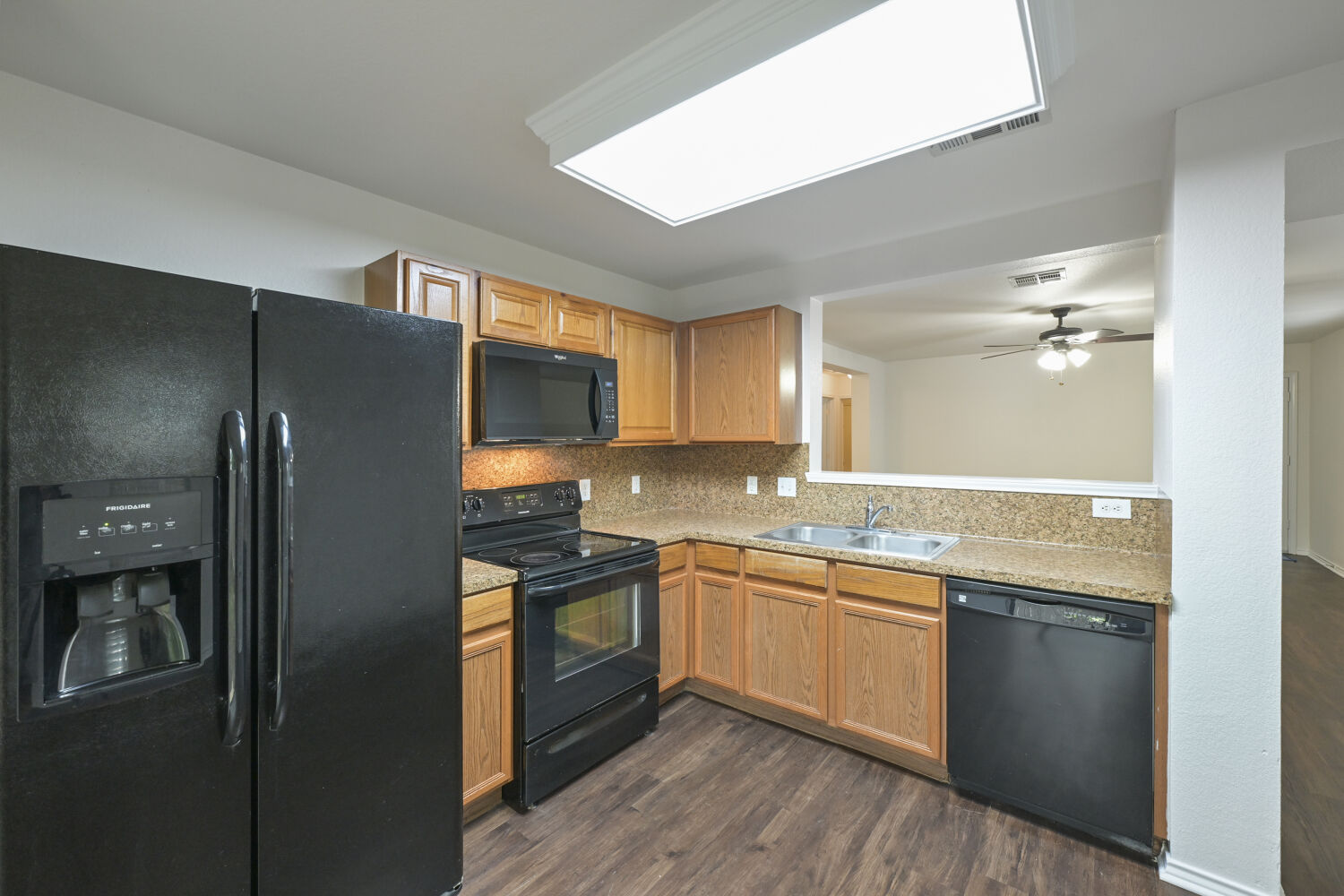 6733 Doyal Drive Austin, TX 78747 - Photo 20 of 28 A well-appointed kitchen features rich wood cabinetry, granite-style countertops, and modern black appliances.