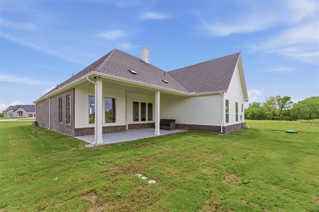 2433 Meteor Drive Krum, TX 76249 - Photo 26 of 29 Expansive backyard featuring a covered patio with concrete flooring, support columns, and a shingle roof