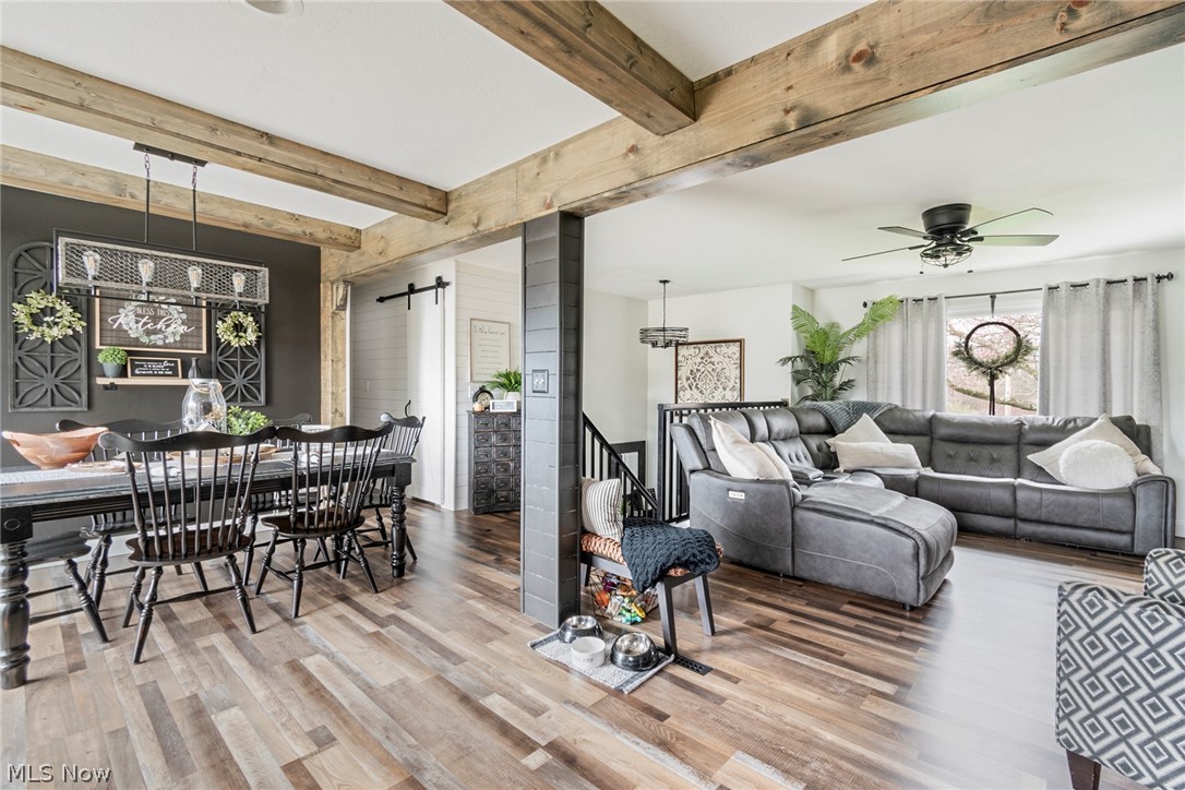 3792 South Raccoon Road Canfield, OH 44406 - Photo 15 of 39 Living room featuring a barn door, beam ceiling, light wood-type flooring, and ceiling fan with notable chandelier