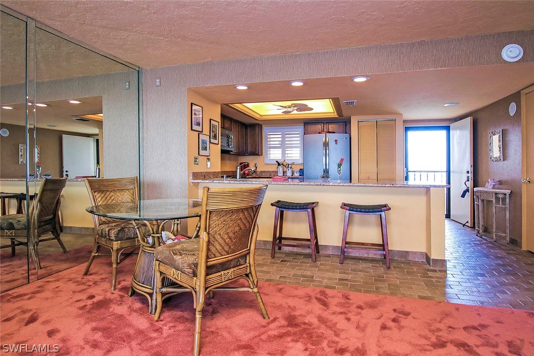 15021 Punta Rassa Road, Unit 602 Fort Myers, FL 33908 - Photo 4 of 35 a dining hall with stainless steel appliances a dining table and chairs with kitchen view