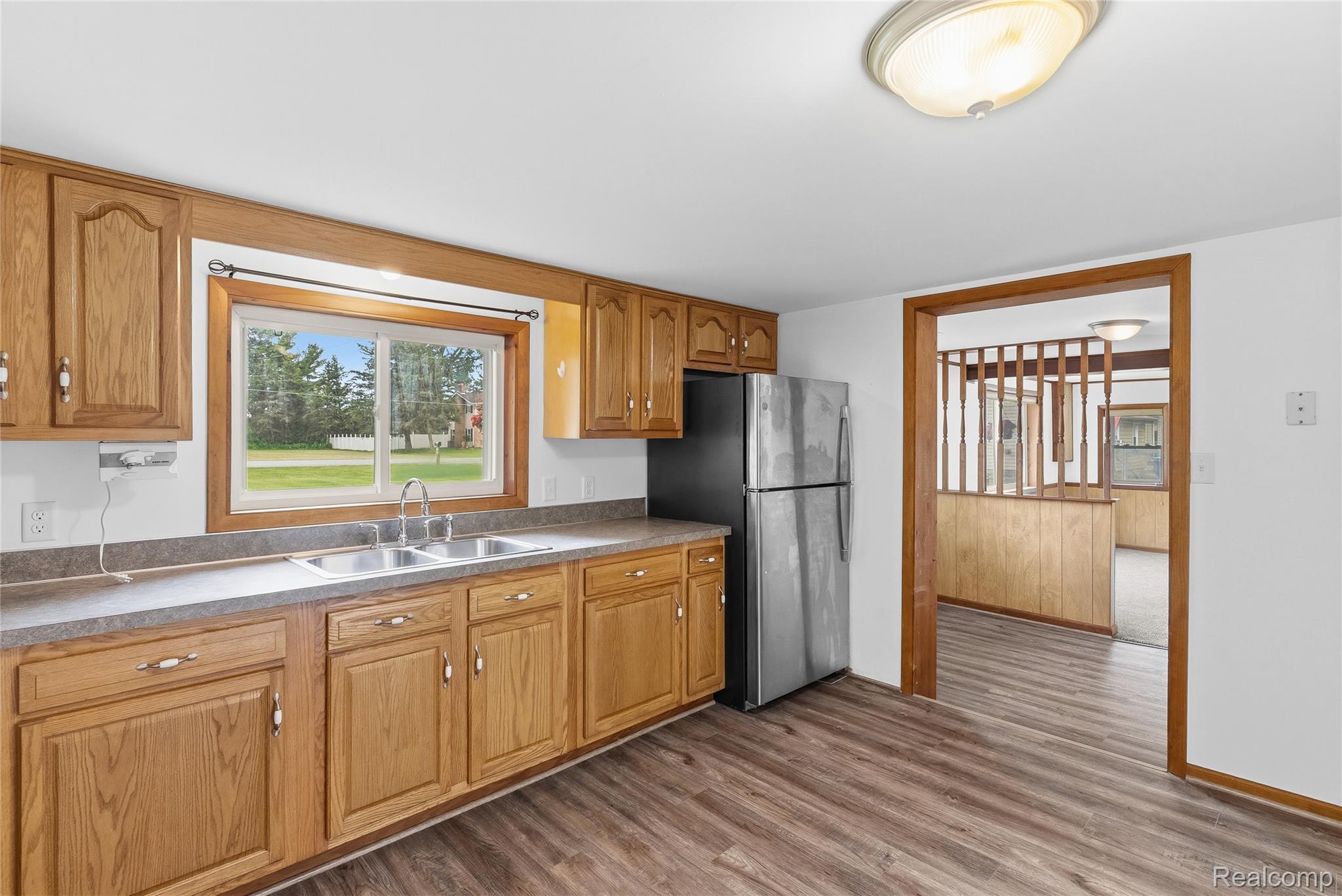 1843 Curtis Road Birch Run, MI 48415 - Photo 8 of 25 Kitchen featuring wood-finish flooring, wood cabinetry with decorative hardware, a double basin stainless steel sink, and a stainless steel refrigerator