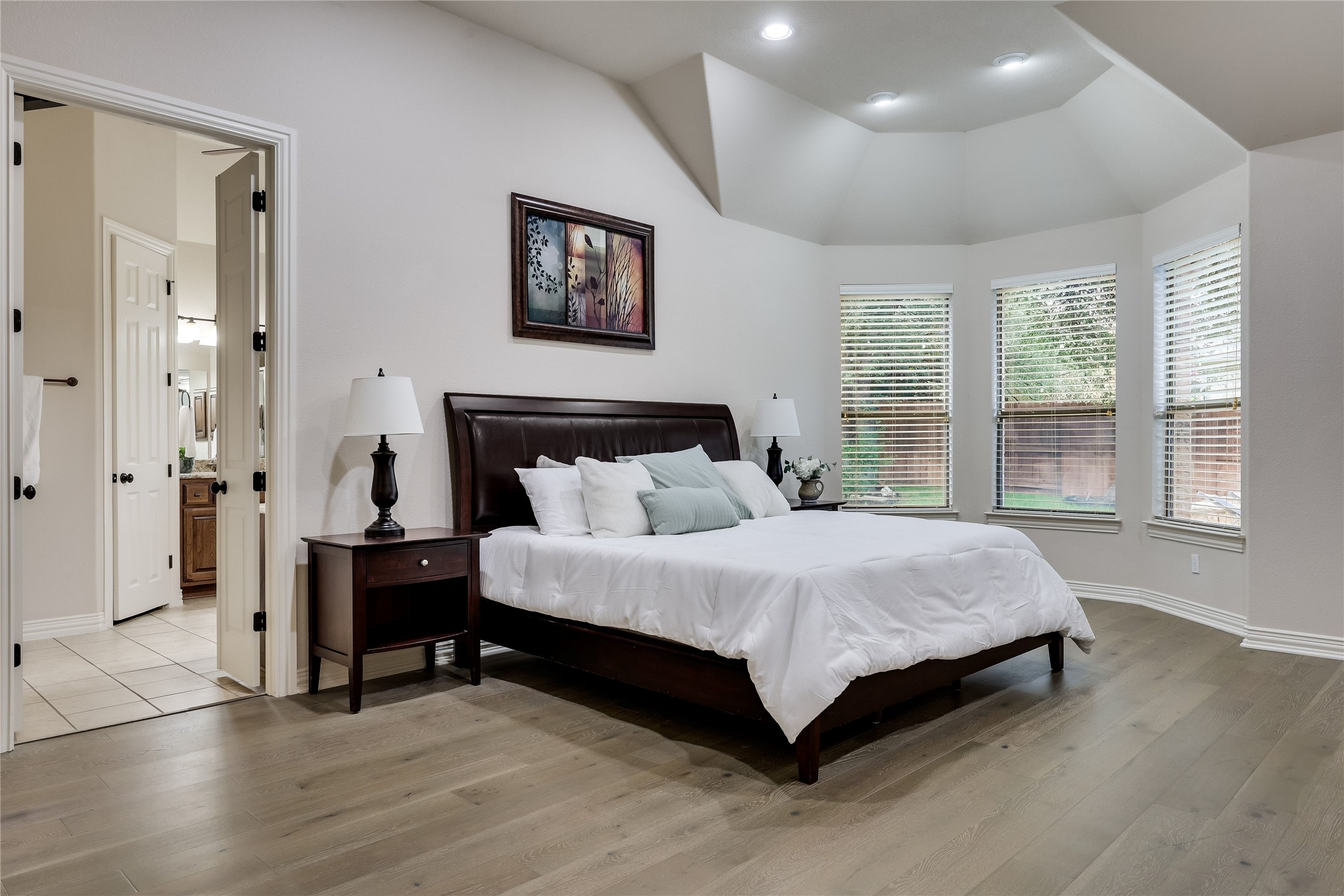 408 Ridgetop Bend Cedar Park, TX 78613 - Photo 23 of 40 A tranquil primary bedroom with vaulted ceilings, recessed lighting, and rich hardwood flooring, offering serene views.