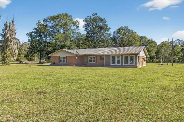 a front view of house with yard and trees in the background