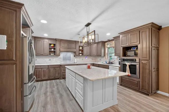 a kitchen with stainless steel appliances granite countertop a refrigerator a stove and a sink