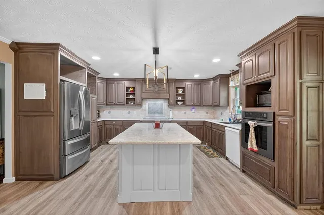 a kitchen with kitchen island granite countertop stainless steel appliances cabinets a sink and a counter space