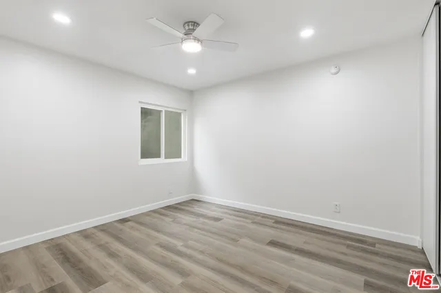 an empty room with a window and ceiling fan