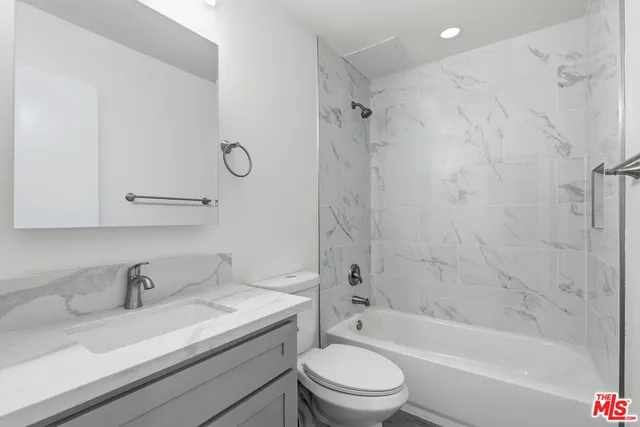 a bathroom with a granite countertop sink a toilet and a bathtub