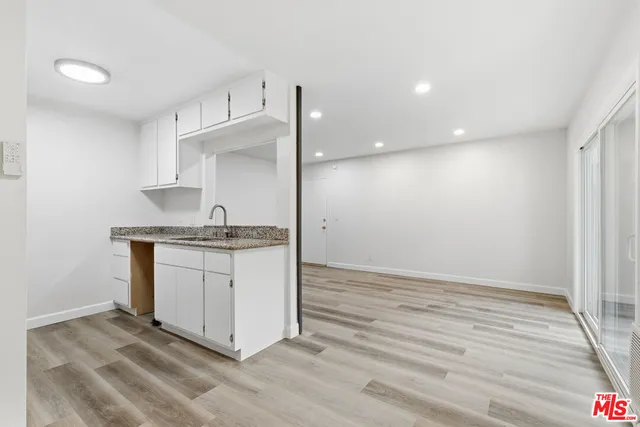 a room with granite countertop white cabinets and a sink