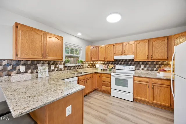 a kitchen with stainless steel appliances granite countertop a stove a sink and white cabinets with wooden floor