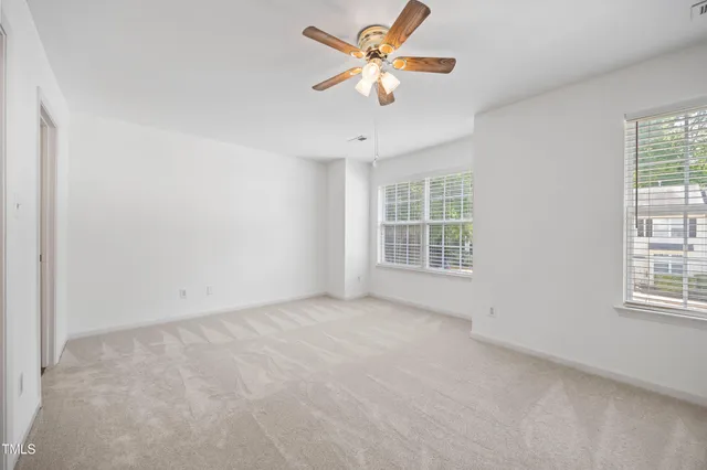 an empty room with windows and fan