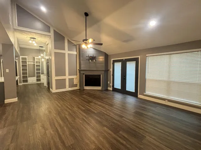 a view of a room with wooden floor fireplace and windows