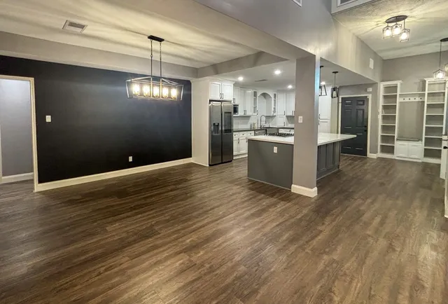 a view of an empty room with kitchen and window