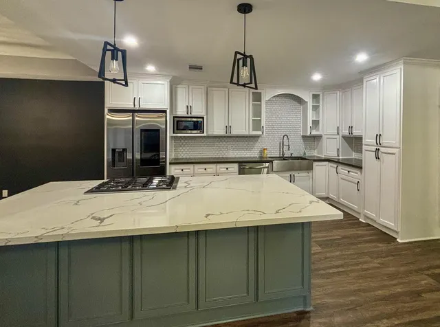a kitchen with kitchen island a sink a stove a refrigerator and cabinets