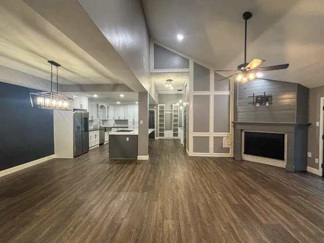 a view of a room with wooden floor and a kitchen