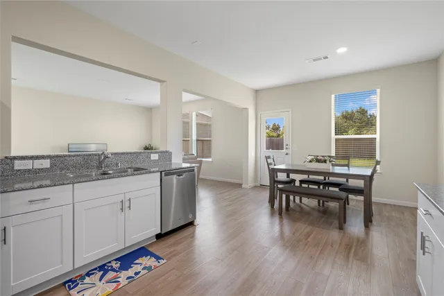 a open kitchen with granite countertop a dining table chairs and wooden floor