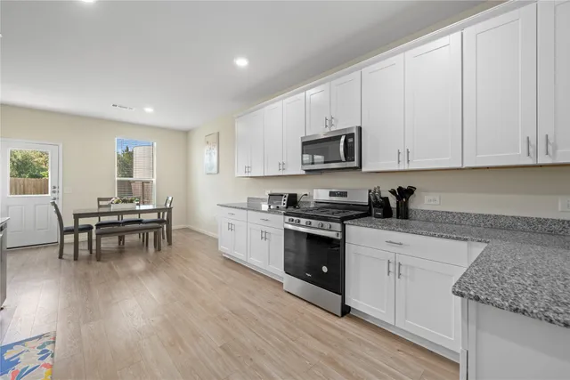 a kitchen with microwave a stove and white cabinets